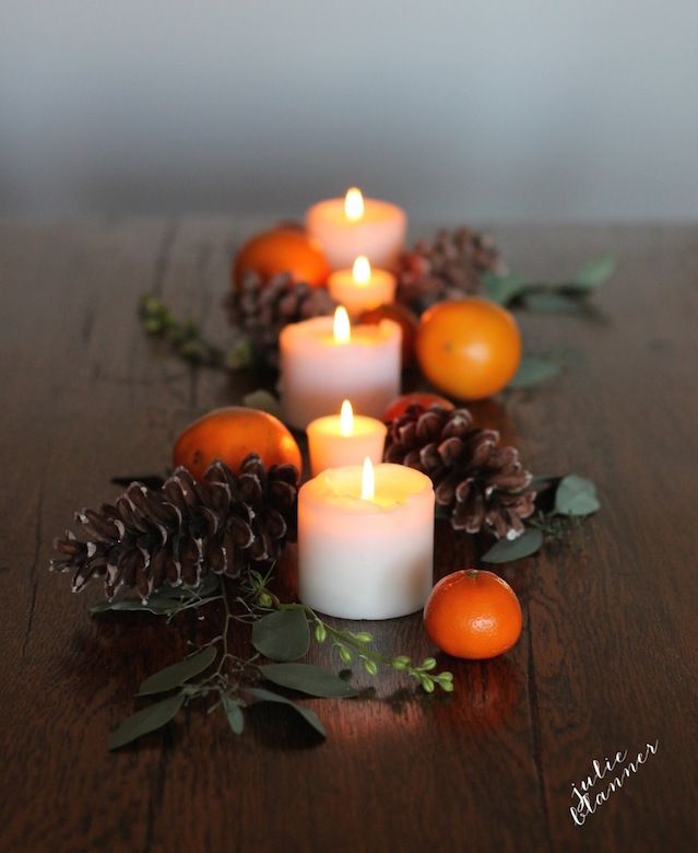 Clementines and pinecones dress up votive candles for an easy, last-minute Thanksgiving table setting | Julie Blanner